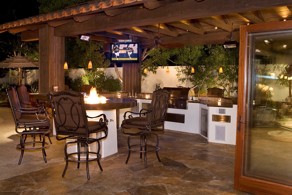 Polished and sealed concrete countertops, complete with cracks and uneven color, continued the rustic look of the large U-shaped outdoor kitchen.