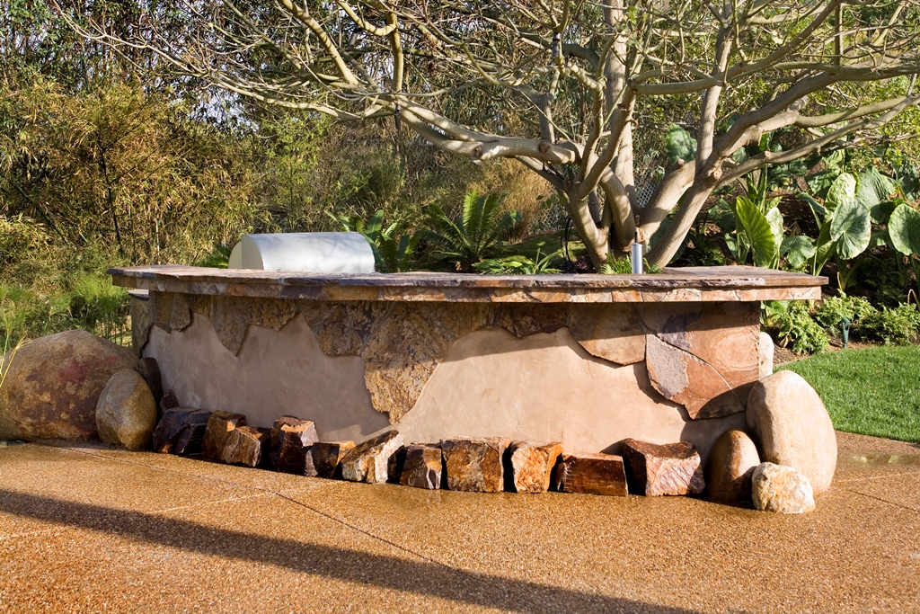 Incorporating the same materials as the pool, a stone footrest frames the base of the stucco wall that matches the house.